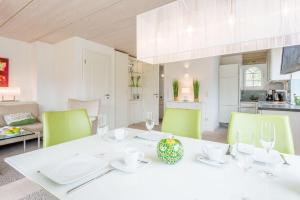 uma sala de jantar com uma mesa branca e cadeiras verdes em Haus Nordgang 8 Haushaelfte B em Westerland