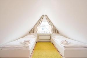 two beds in a small room with a window at Haus Nordgang 8 Haushaelfte B in Westerland (Sylt)