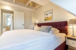 Schlafzimmer mit einem großen weißen Bett mit einem roten Kopfteil in der Unterkunft Süster Hüs in Westerland