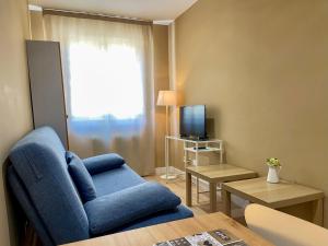 uma sala de estar com uma cadeira azul e uma televisão em Casablanca Hotel Studios em Santa Marta de Tormes