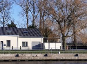 Biały dom z czarnym dachem i drzewem w obiekcie vakantiehuis Plassendale w mieście Oudenburg