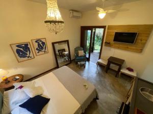 a bedroom with a bed and a living room with a tv at Pousada Santarina in Florianópolis