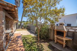 a patio with a fireplace and a tree in a yard at Villa Paulina in Sant Martí d'Empúries