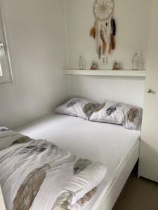 een slaapkamer met een bed met witte lakens en een plank bij Luxe Chalet Marbella IJmuiden aan Zee in IJmuiden