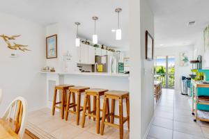 a kitchen with white cabinets and wooden stools at Beachside Drive 14 in Isle of Palms +27 photos