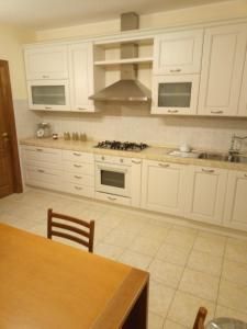 cocina con armarios blancos, mesa y fogones en A CASA DI LUCA E GLORIA 2 en Giulianova