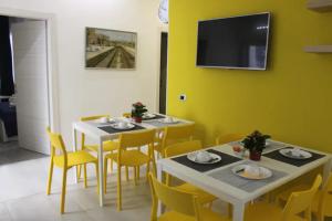 ein Esszimmer mit 2 Tischen und gelben Stühlen in der Unterkunft B&B CaselloA Suites in Syrakus