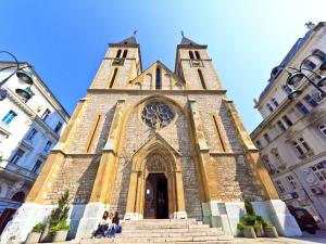 une église avec une haute tour dans une ville dans l'établissement Bascarsija Corner, à Sarajevo