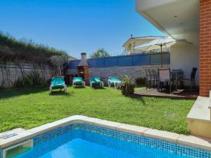 a backyard with a swimming pool and a lawn with chairs and tables at V3, Villa Jardins Branqueira6 near Beach, Albufeira in Albufeira