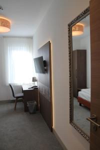einen Spiegel in einem Hotelzimmer mit einem Bett und einem Schreibtisch in der Unterkunft Hotel Landgasthof Gemmer in Rettert