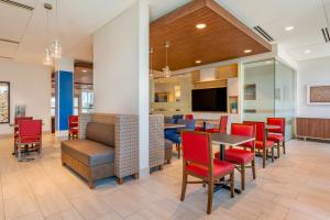 une salle à manger avec des chaises rouges, des tables et une télévision dans l'établissement Holiday Inn Express & Suites - Phoenix Dwtn - State Capitol, an IHG Hotel, à Phoenix