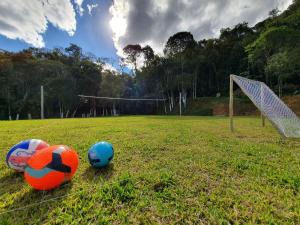 three soccer balls on a field with a goal at Sítio Pedacinho do Céu na Serra Catarinense in Rancho Queimado