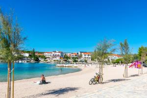 a man sitting on a beach next to the water at Apartment Kucinic in Rogoznica