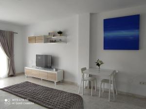 1 dormitorio con cama, mesa y TV en BenalSuite estudio, piscina y playa en BenalBeach, Benalmadena en Benalmádena