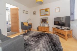 a living room with a couch and a flat screen tv at Scalpay@Knock View Apartments, Sleat, Isle of Skye in Teangue