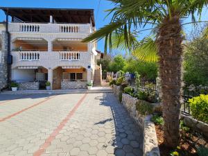 a house with a palm tree in front of it at Apartments NEF in Pinezici