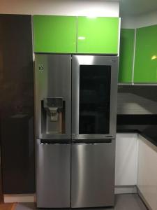 a stainless steel refrigerator in a kitchen with green cabinets at Misuitehotel La Carolina Quito in Quito