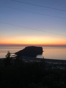 una puesta de sol sobre el océano con una roca en el agua en Villa Cataleya, en Praia a Mare
