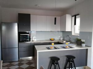 a kitchen with white cabinets and a counter with bar stools at Apartments Jelka in Postira