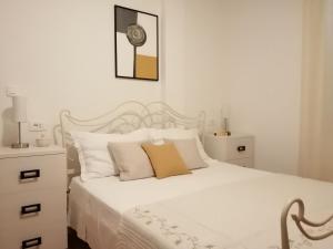 a white bedroom with a white bed with white pillows at Apartments Jelka in Postira