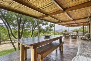 einen großen Holztisch auf einer Terrasse mit Blick auf die Bäume in der Unterkunft Waterfall Farm Self-Catering Cottages Citrusdal in Citrusdal