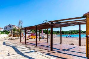 a pavilion on a sandy beach with a pool at Apartments Zdravko in Rogoznica