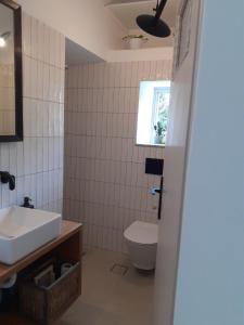 ein Bad mit einem Waschbecken, einem WC und einem Fenster in der Unterkunft Maria’s Cottage House in Kalymnos