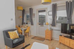 un soggiorno con TV, sedia e tavolo di Pabay@Knock View Apartments, Sleat, Isle of Skye a Teangue