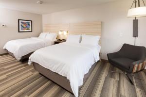 ein Hotelzimmer mit 2 Betten und einem Stuhl in der Unterkunft Holiday Inn Express Hotel & Suites Logansport, an IHG Hotel in Logansport