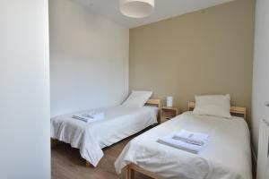 2 camas en una habitación con sábanas blancas en Welcome Home, en Linas