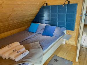 a bed in a wooden cabin with blue pillows at Zacisze Kopalino in Kopalino
