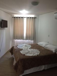 a bedroom with a large bed with a brown blanket at Pousada Beija Flor Centro in Gramado