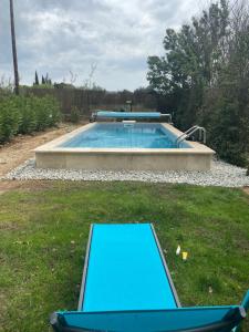 a pool in a yard with two chairs in the grass at STUDIO Havre de paix au pont du gard Piscine et Jacuzzi chez Valerie Payre in Vers Pont du Gard