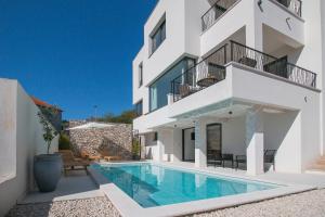 a house with a swimming pool in front of a building at Villa Sea Silhouette in Žman