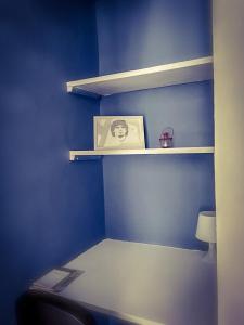 ein blaues Zimmer mit einem Regal mit einem Bild darauf in der Unterkunft Casa vacanze Caterina in Neapel