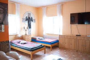 a living room with two beds and a cross on the wall at Pension SXF in Schönefeld
