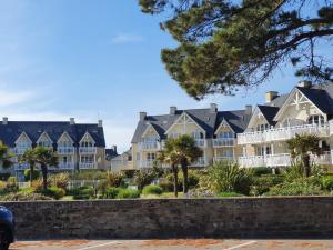 eine Reihe von Häusern mit Palmen davor in der Unterkunft Vacances Ô Cap Coz - Jardin vue mer et piscine - Résidence Cap Azur Fouesnant in Fouesnant