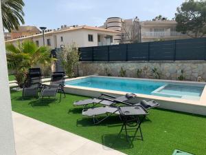 einen Hinterhof mit einem Pool und Stühlen sowie einem Tisch und einem Pool in der Unterkunft Amazing house close to the beach in Port d'Alcúdia