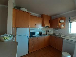 a kitchen with wooden cabinets and a white refrigerator at VP Flat with Balcony and Pool View in Alvor