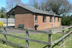 a small brick house with a wooden fence at Swallows Retreat in Fordingbridge