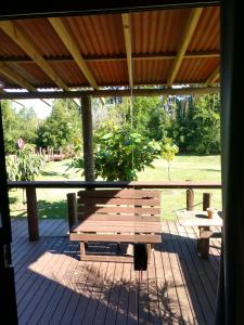 a wooden bench sitting on a porch with a view of a park at Pousada Casa de Ferro in Passo de Torres