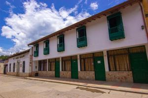 a building with green doors and windows on a street at Hotel Cacique Chalalá in Charalá