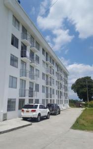 a white building with two cars parked in a parking lot at Apartamentos y Piscina a 3 min del Parque Cafe in Montenegro