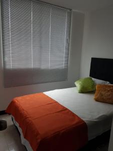 a bedroom with a bed with orange and green pillows at Apartamentos y Piscina a 3 min del Parque Cafe in Montenegro