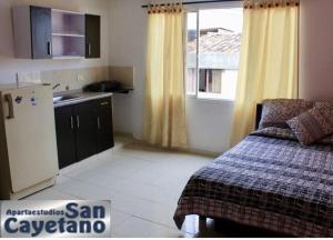 eine kleine Küche mit einem Bett und einem Kühlschrank in der Unterkunft ApartaEstudios San Cayetano Cali in Cali