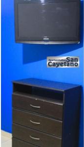 een tv op een dressoir met een blauwe muur bij ApartaEstudios San Cayetano Cali in Cali