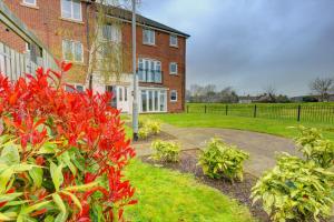 ceglany dom z czerwonymi krzakami przed nim w obiekcie 2-BR Apartment, En-suite, Allocated Parking, next to Playground w Coventry