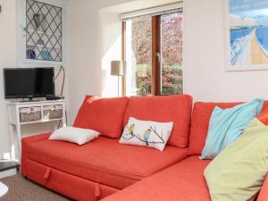 a red couch with pillows on it in a living room at Spring Cottage in Ilfracombe