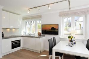eine weiße Küche mit einem weißen Tisch und ein weißes Esszimmer in der Unterkunft Haus Doktor Ross Strasse 31 Whg 4 in Westerland