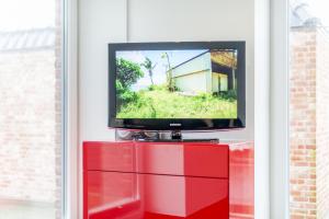 - une télévision assise au-dessus d'une commode rouge dans l'établissement Art your Life Haus Schützenstrasse Whg 2, à Westerland